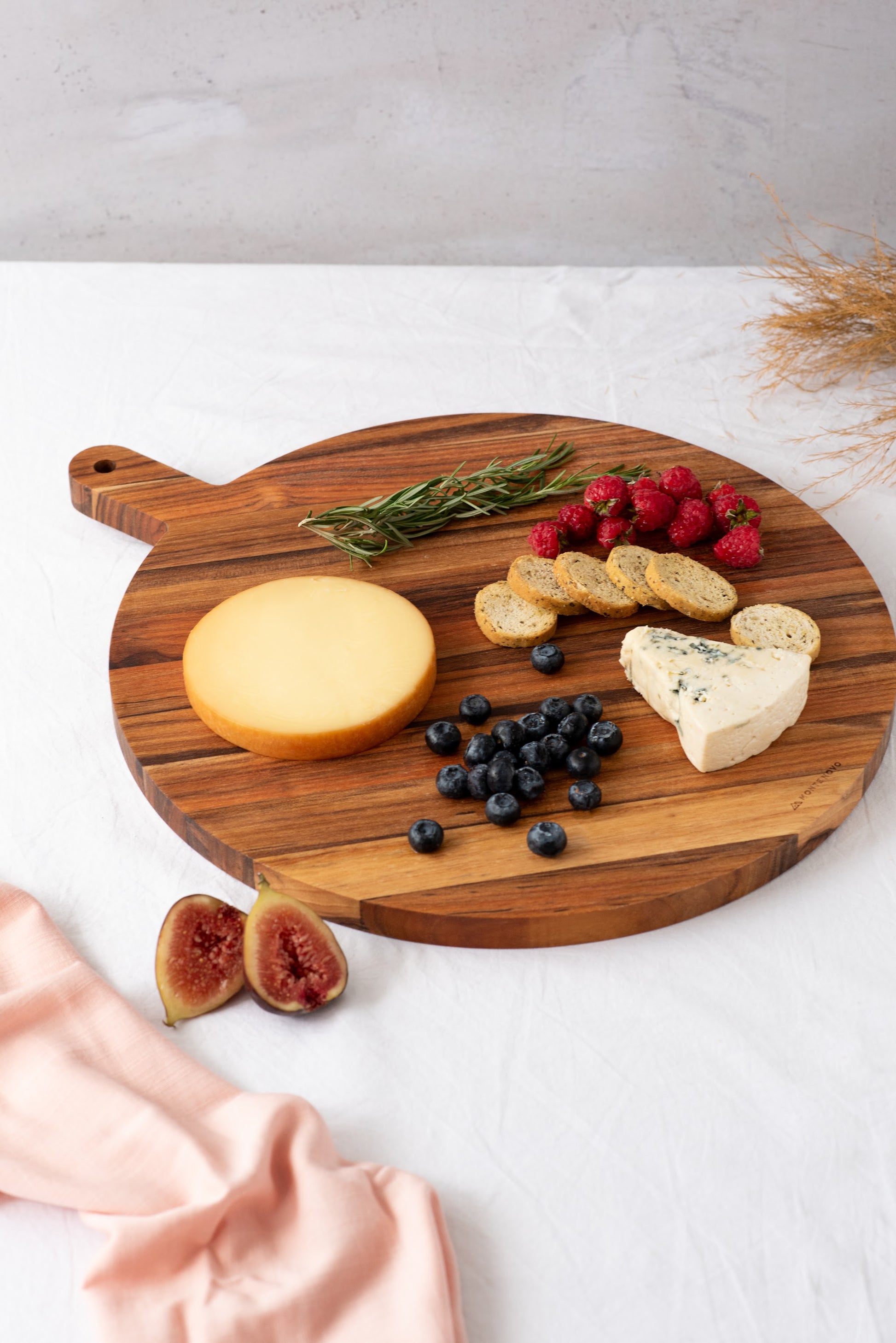 Tábua de servir em madeira teca com queijos e frutas vermelhas sobre a superfície