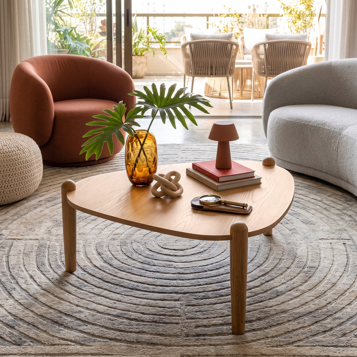 Mesa de centro em sala de estar com poltrona terracota, sofá curvo cinza e tapete redondo