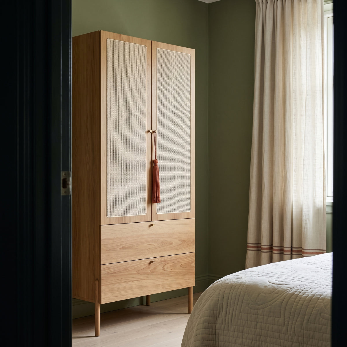 Roupeiro em quarto com parede verde, cortina clara e borla pendurada no puxador