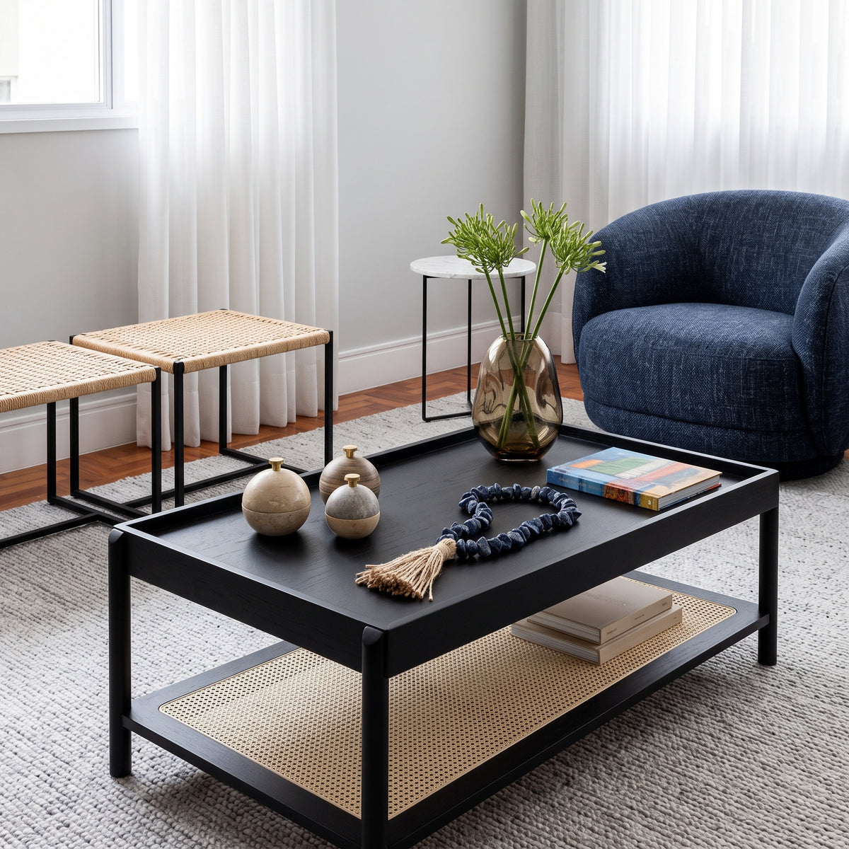Mesa de centro no acabamento Nero em sala de estar com poltrona azul, banquetas de palhinha e tapete cinza