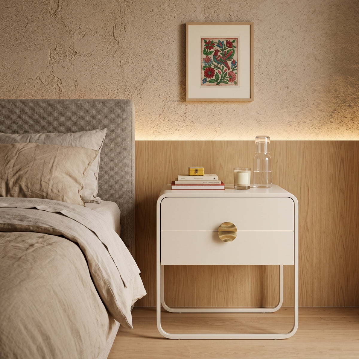 Mesa de cabeceira offwhite com duas gavetas em quarto com cama, painel amadeirado iluminado e quadro florido