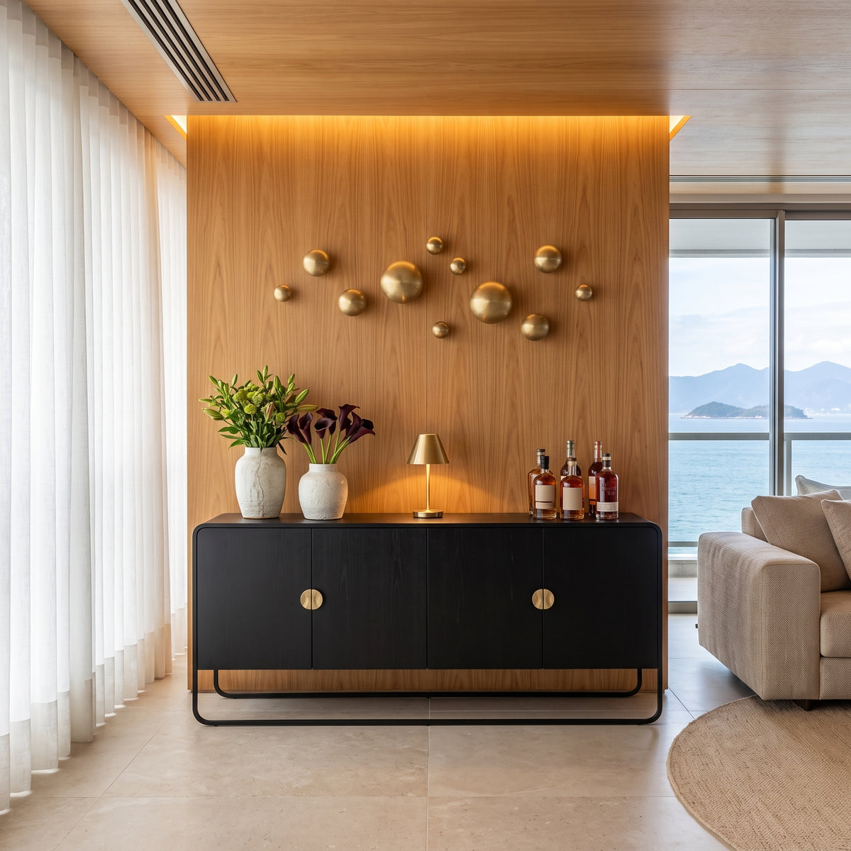 Balcão buffet preto em sala de estar com painel amadeirado, esferas douradas na parede e vista para o mar
