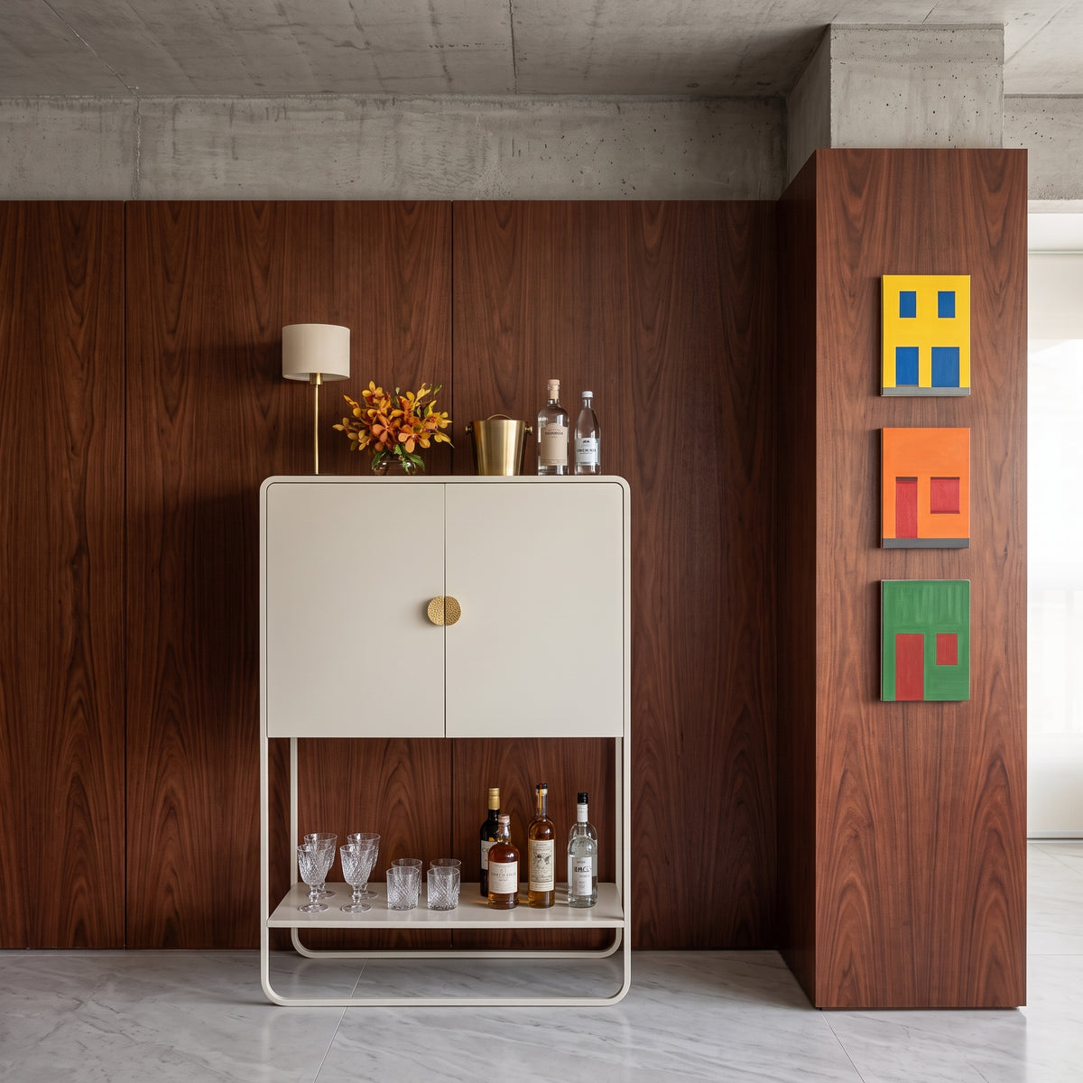 Bar offwhite em sala com painel amadeirado escuro, quadros coloridos e garrafas na prateleira inferior