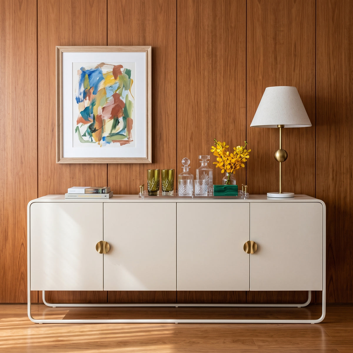 Balcão buffet offwhite em sala com painel amadeirado, quadro colorido, abajur e vaso de flores amarelas