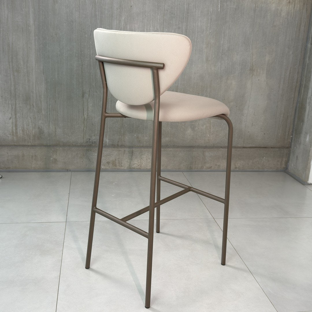 Banqueta alta de encosto curvo e travessas metálicas em ambiente de parede de concreto, vista posterior