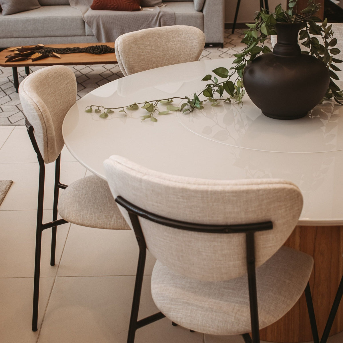 Cadeiras de encosto oval em sala de jantar com mesa redonda de tampo claro e vaso com planta pendente