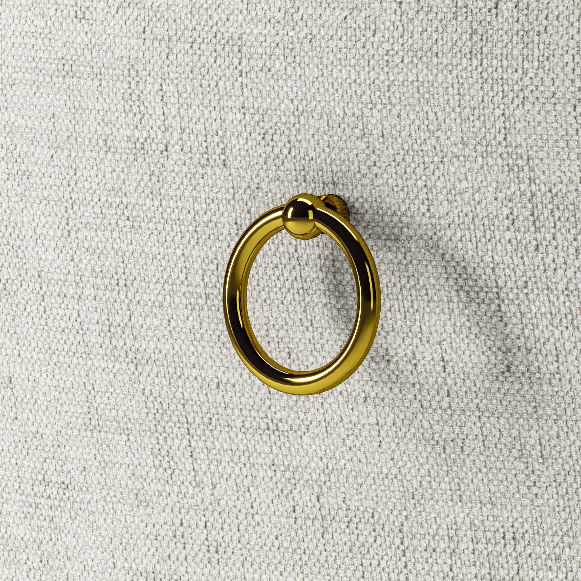 Detalhe do tecido bege e argola dourada presa ao encosto da cadeira.