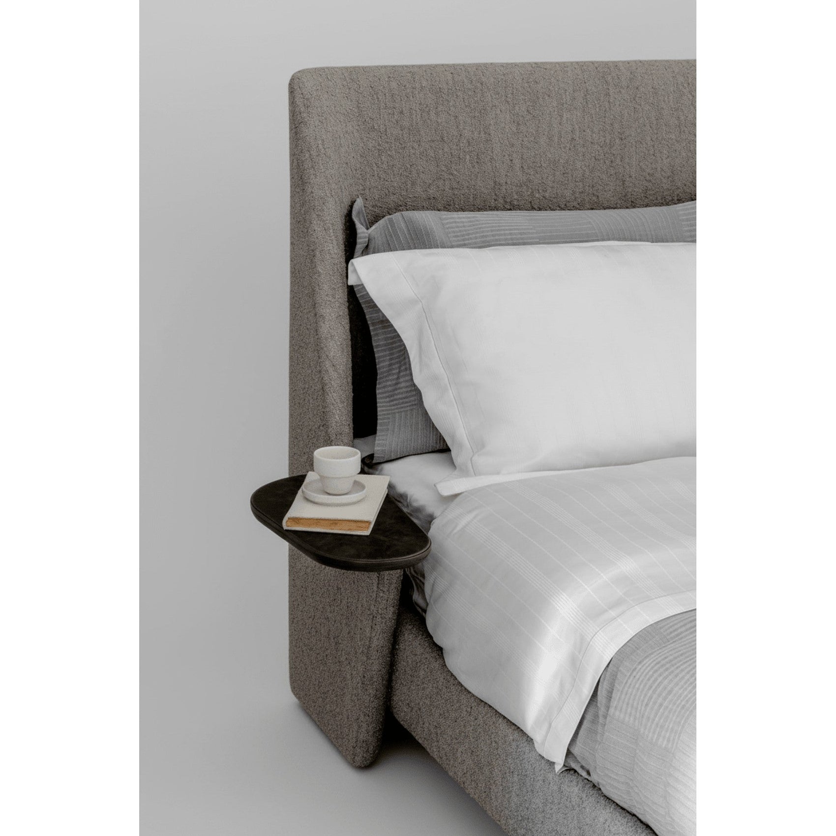 Cama Aura estofada cinza, lateral com apoio alto e roupa de cama branca com tecido liso