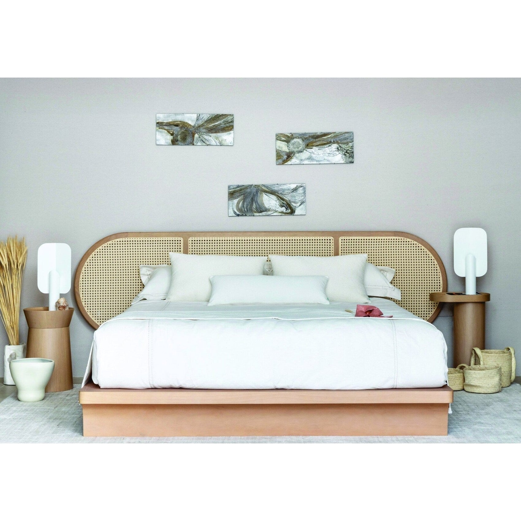 Cama Brisa com roupa de cama branca, cabeceira arredondada de palhinha e apoio lateral.