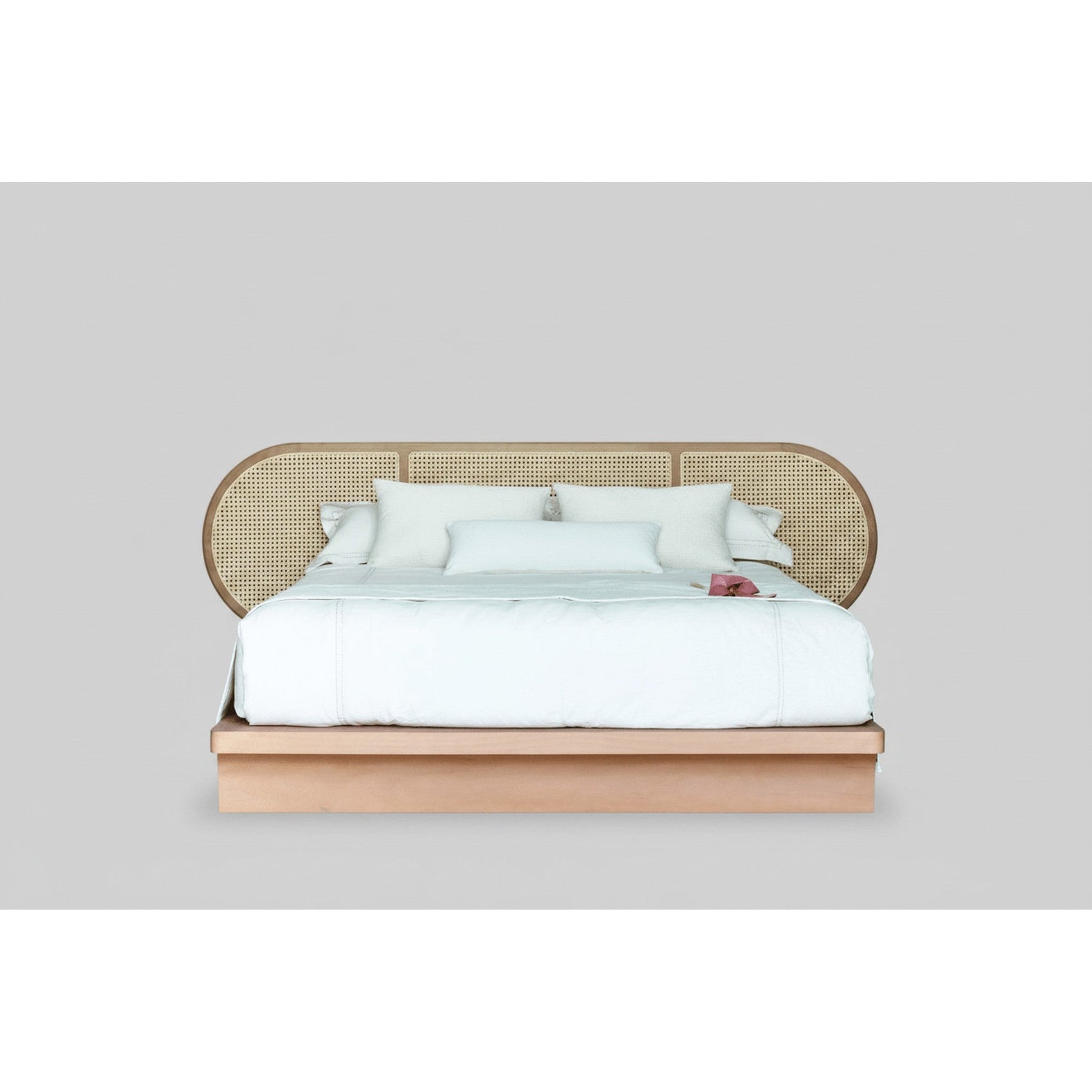 Cama Brisa com cabeceira perfurada de palhinha e lençóis brancos sobre base de madeira.