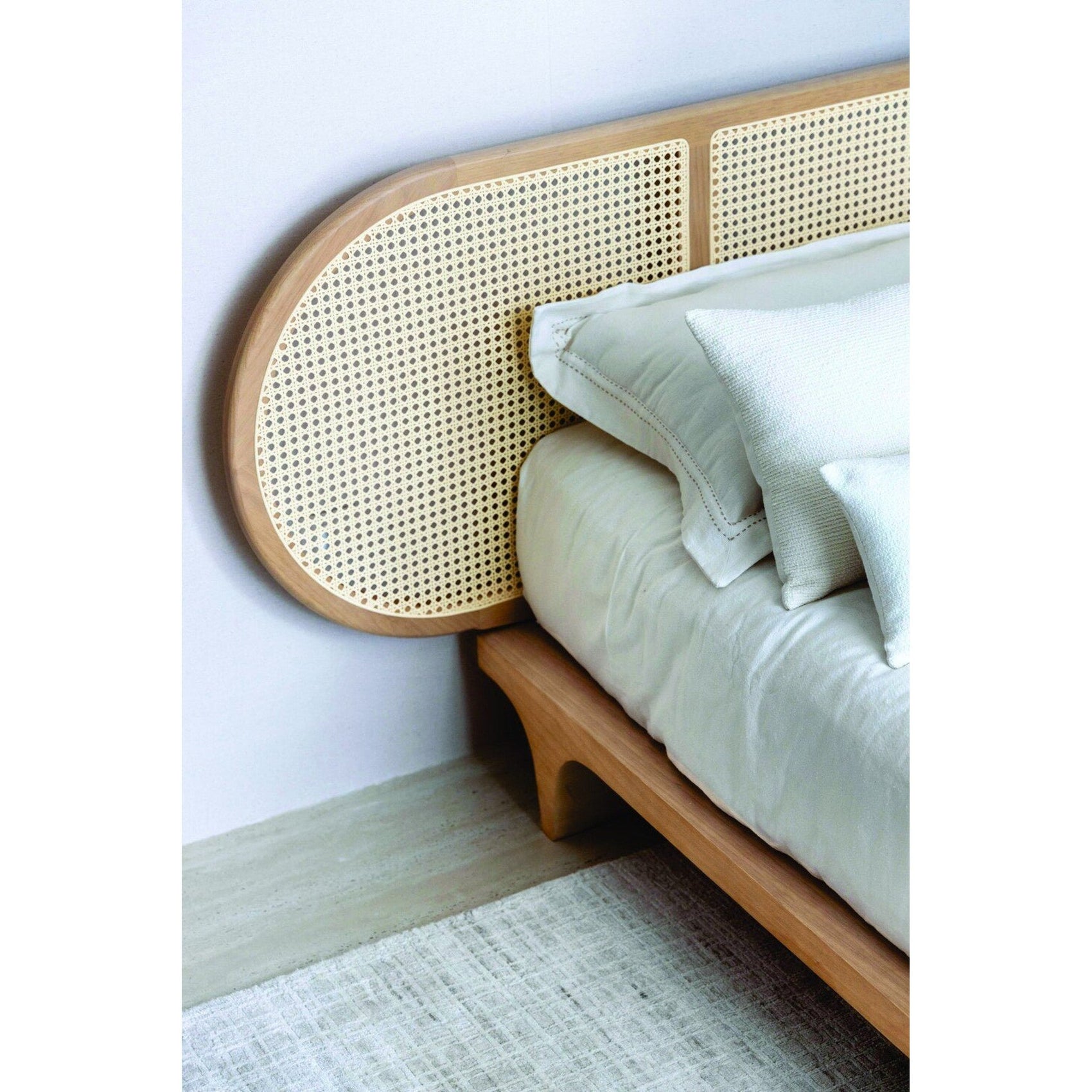 Cama Brisa lateral com cabeceira vazada de palhinha e roupa de cama branca.