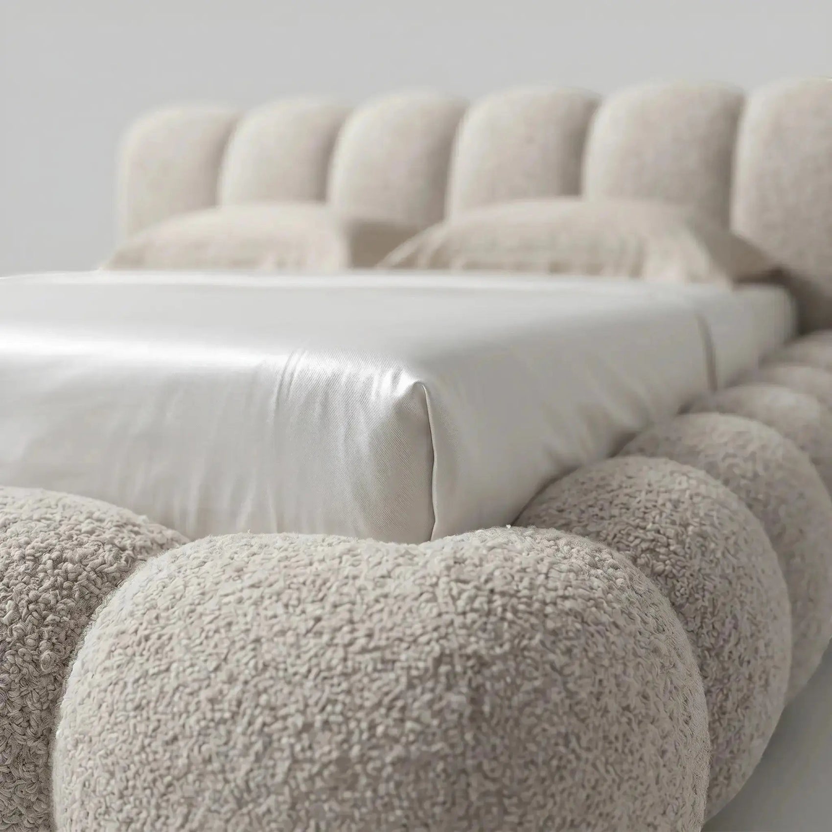 Cama casal estofada bege com cabeceira alta e tecido felpudo, vista próxima