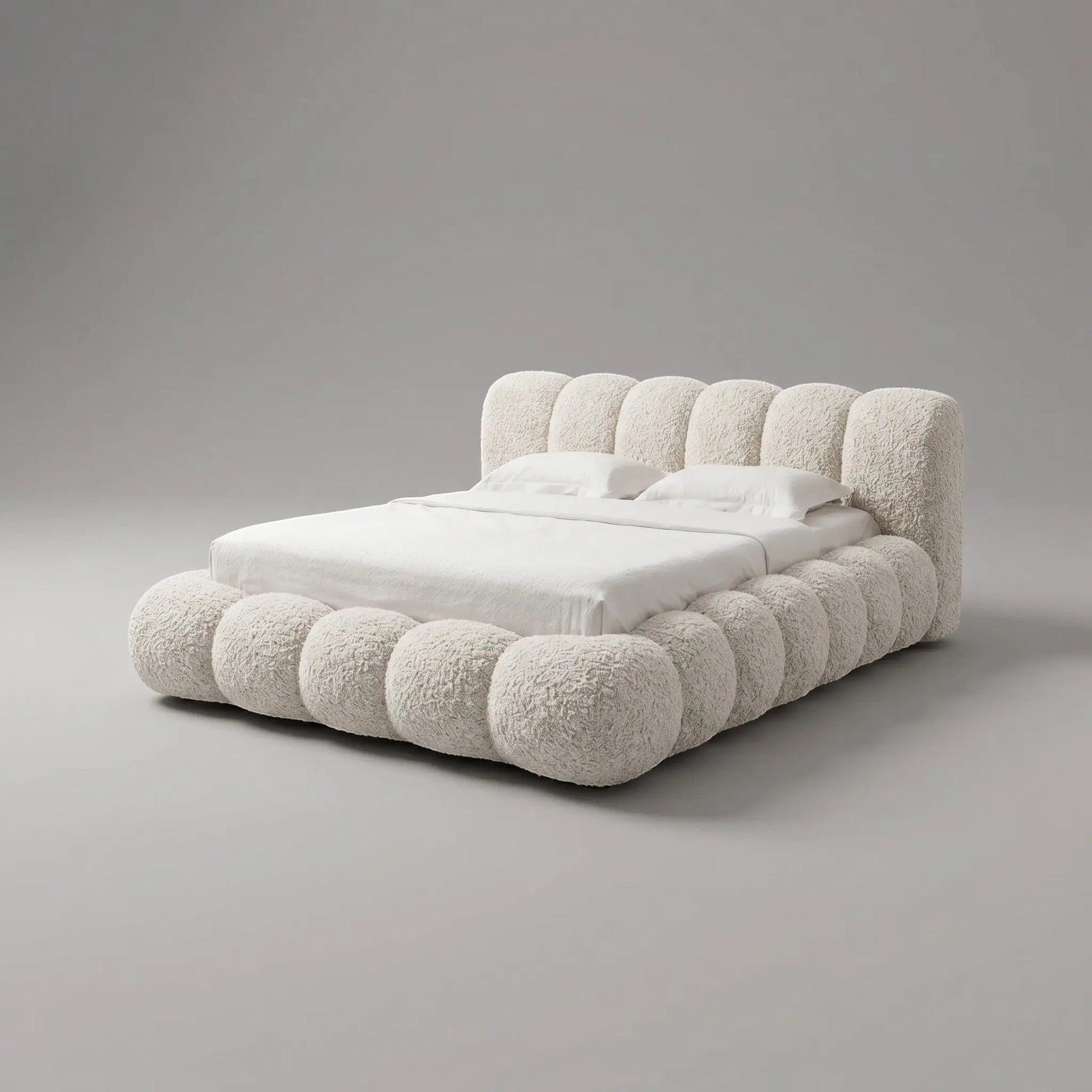 Cama estofada bege claro com cabeceira alta e colchão com lençol branco
