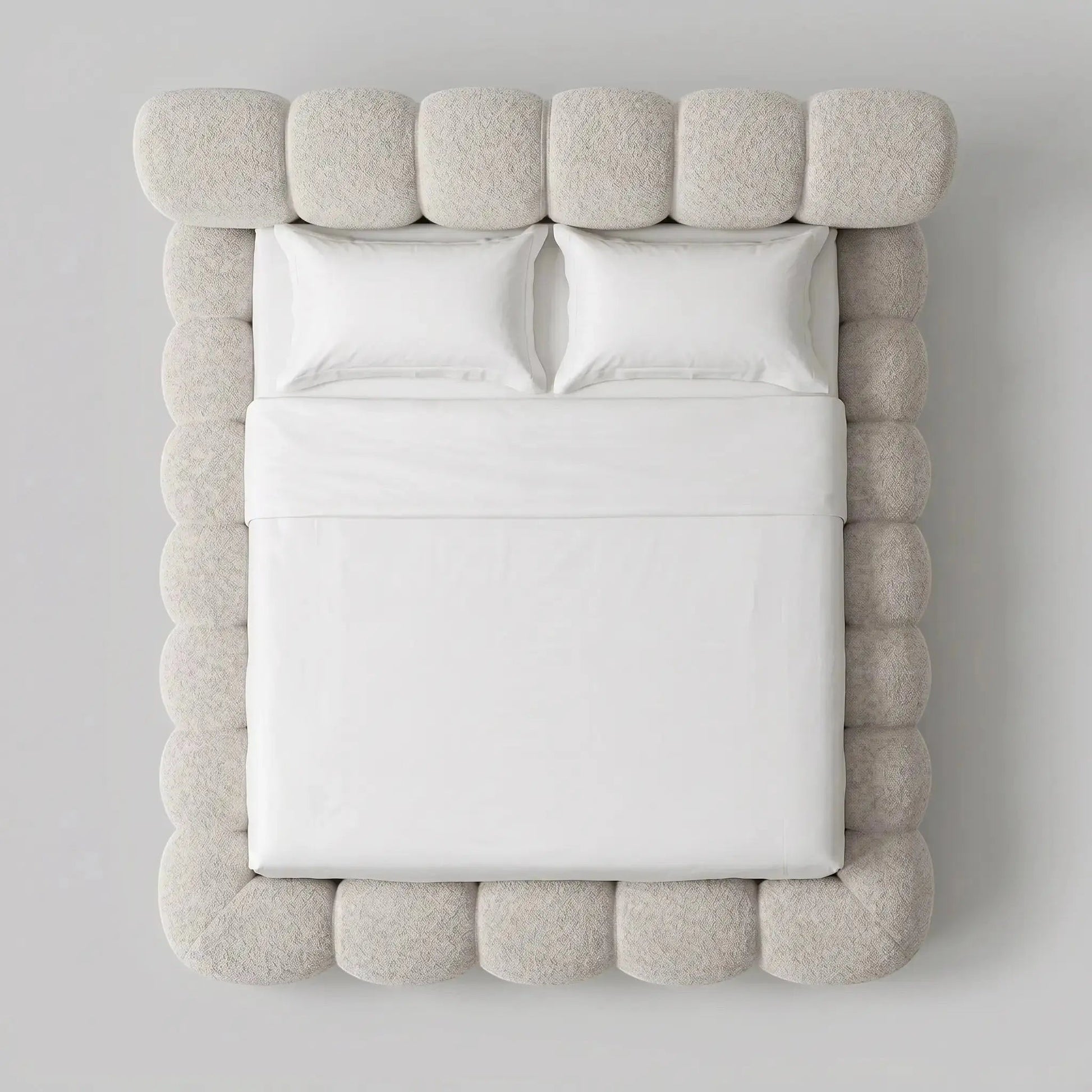 Cama casal estofada bege com quatro almofadas brancas e tecido texturizado