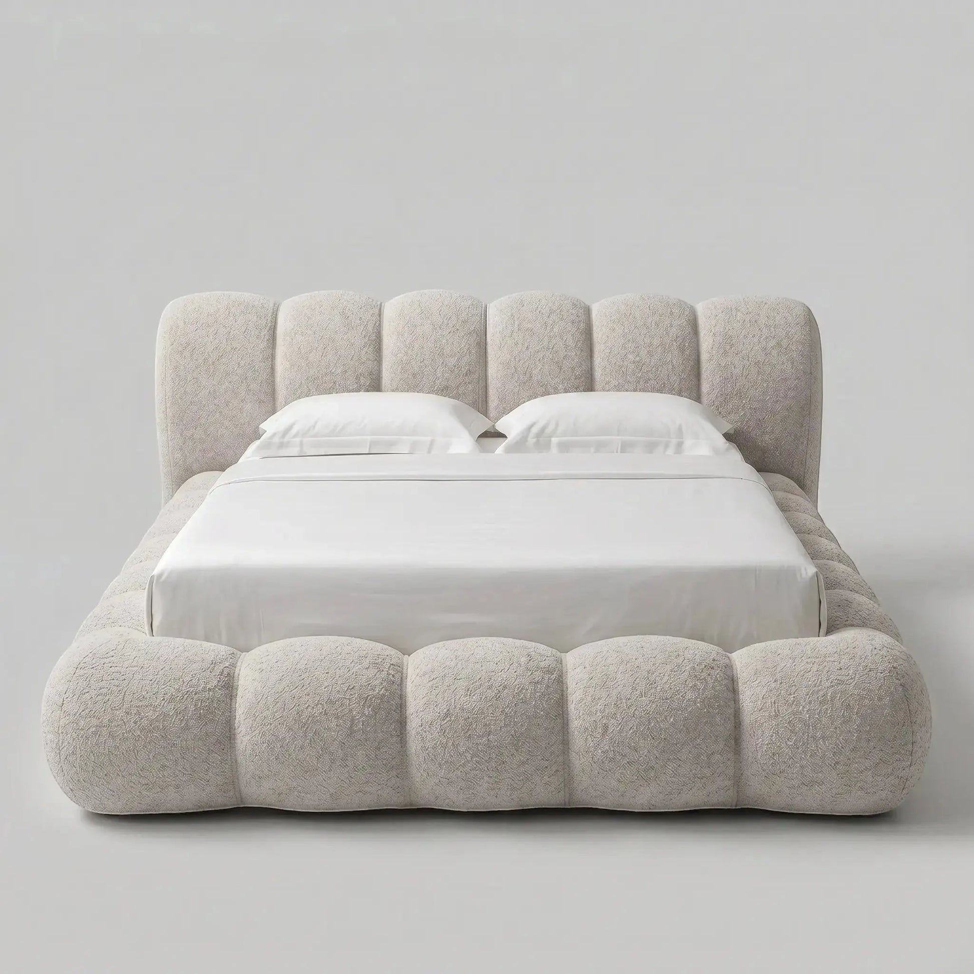 Cama casal estofada bege com base ondulada e lençóis brancos
