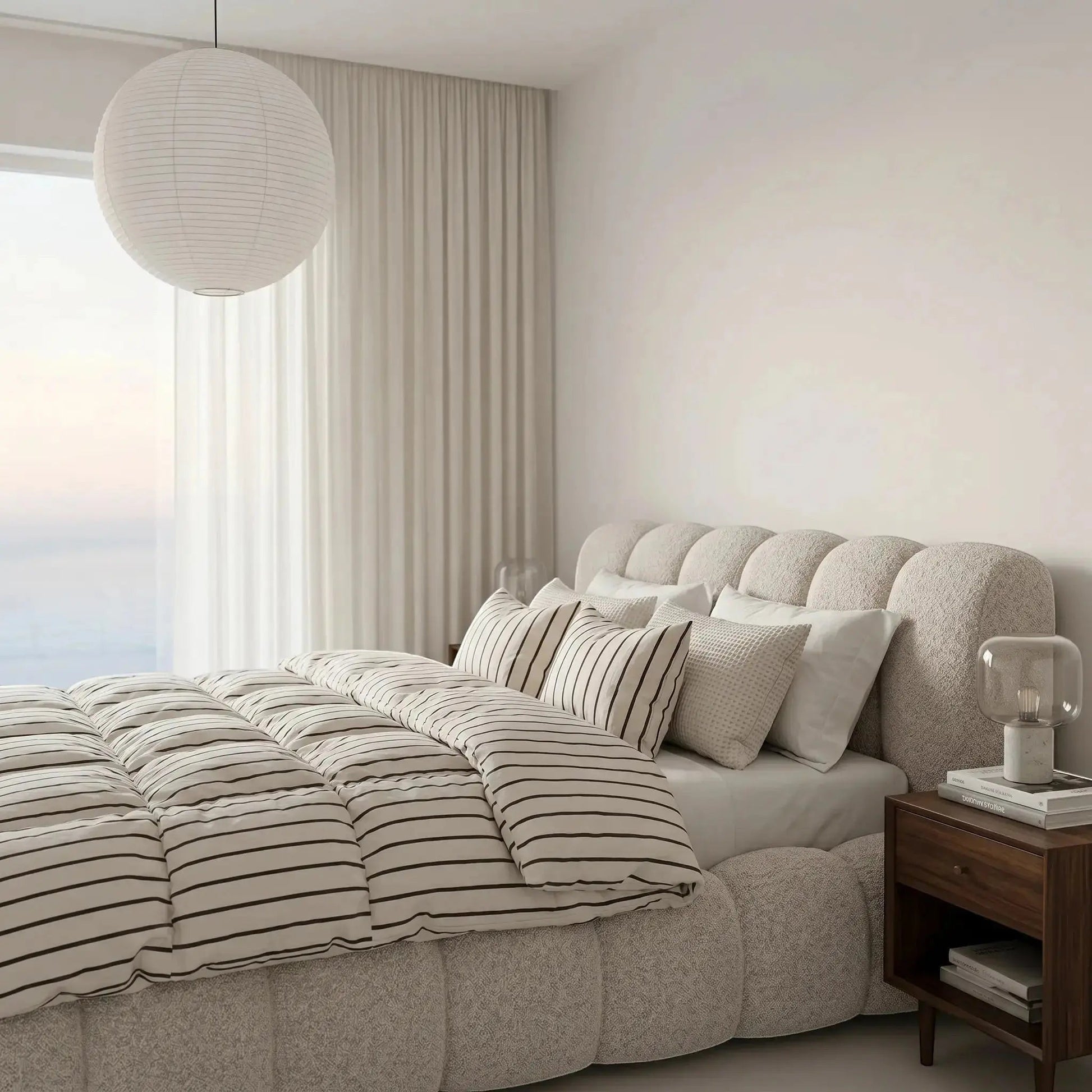 Cama casal estofada bege, cabeceira com formato semicircular e almofadas no assento