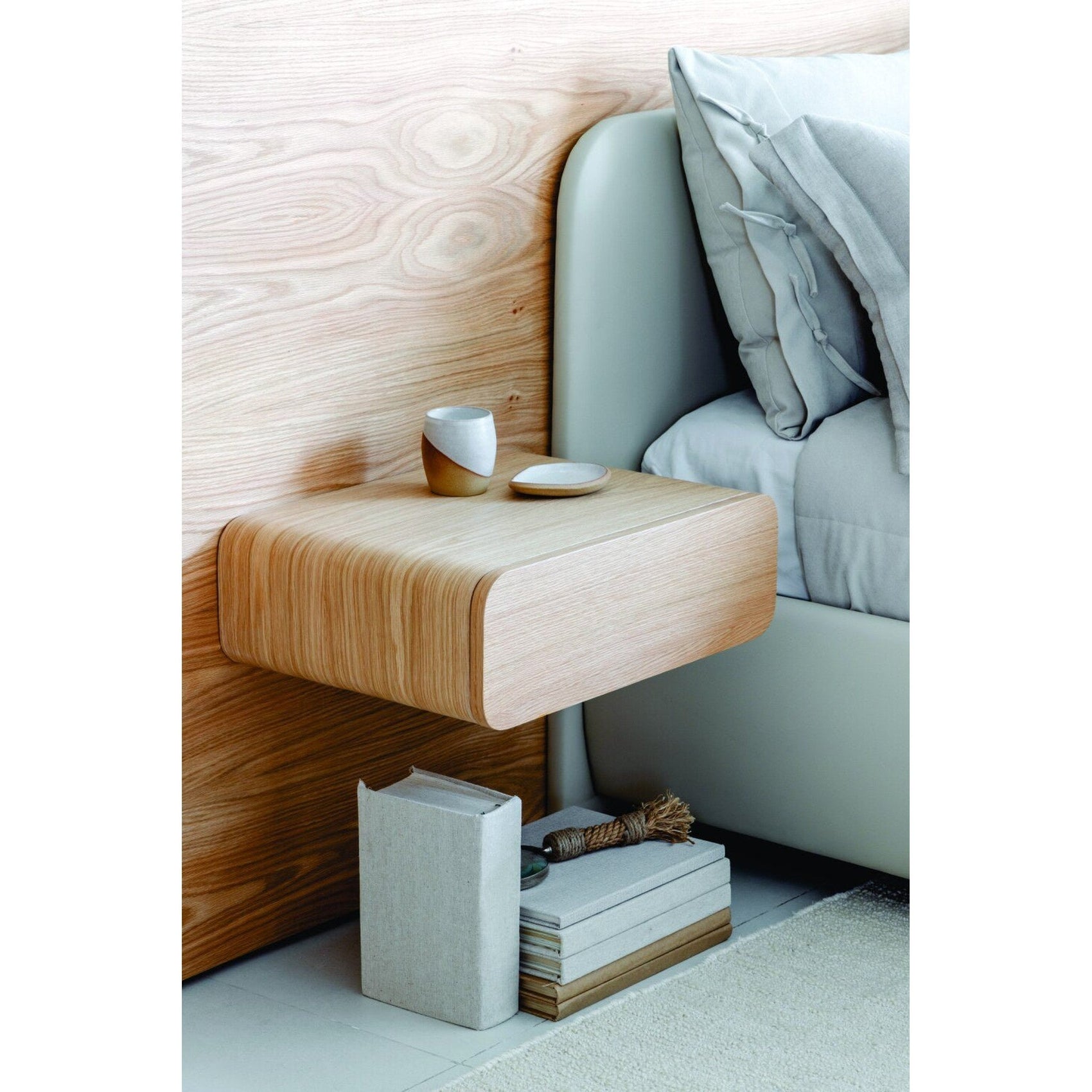 Cama estofada verde-azulada com cabeceira alta e roupa de cama branca