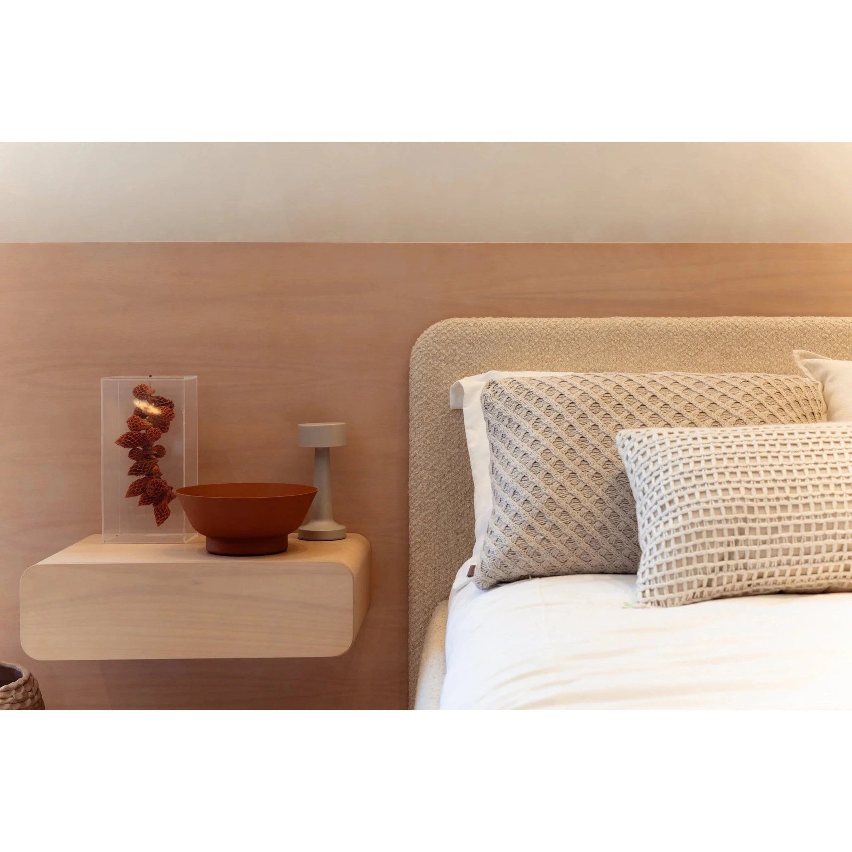 Cabeceira e cama estofada bege com almofadas e colcha claras