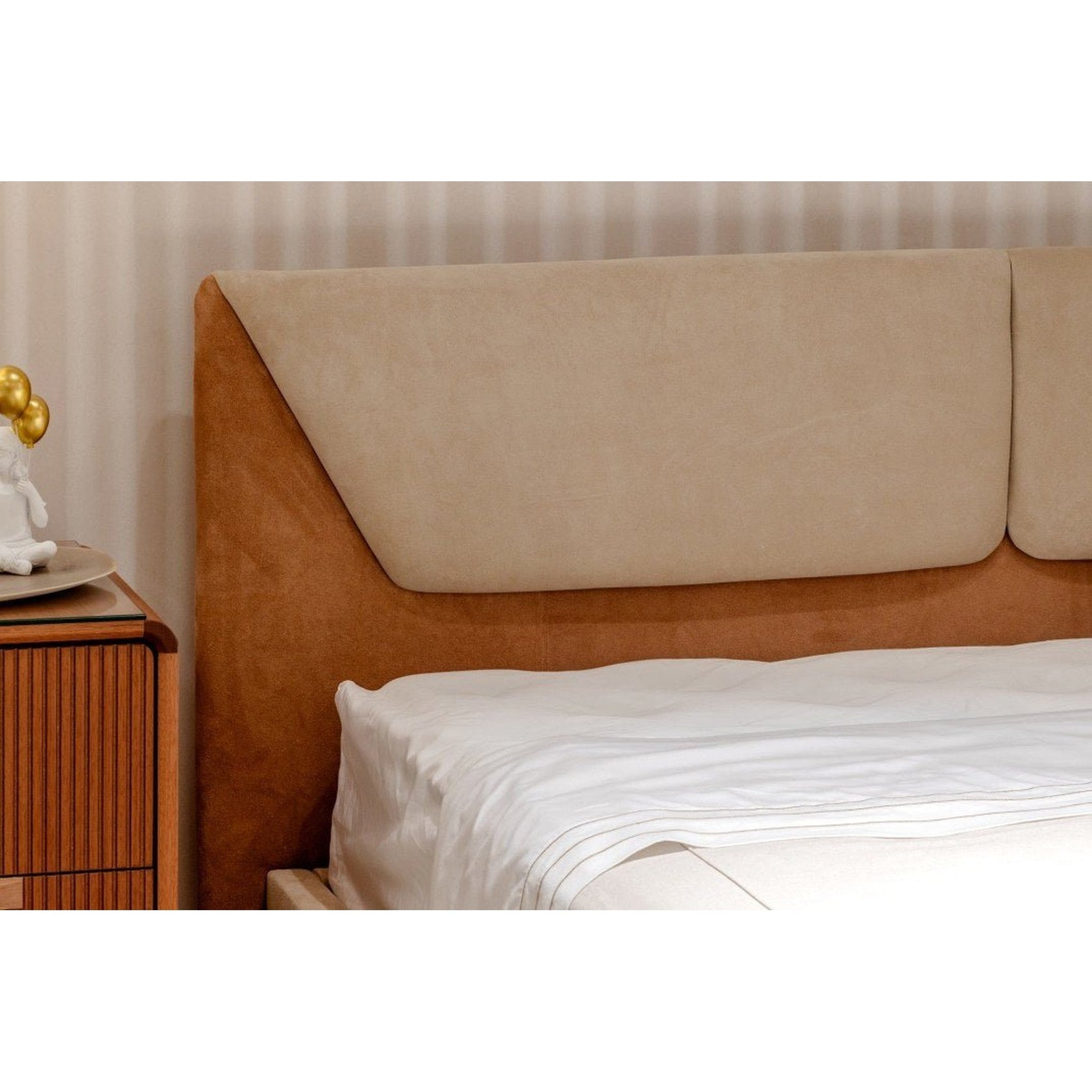 Cabeceira alta estofada em tom escuro com cama e lençol branco, vista lateral.