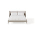 Cama estofada com cabeceira alta cinza e roupa de cama branca com dois travesseiros.