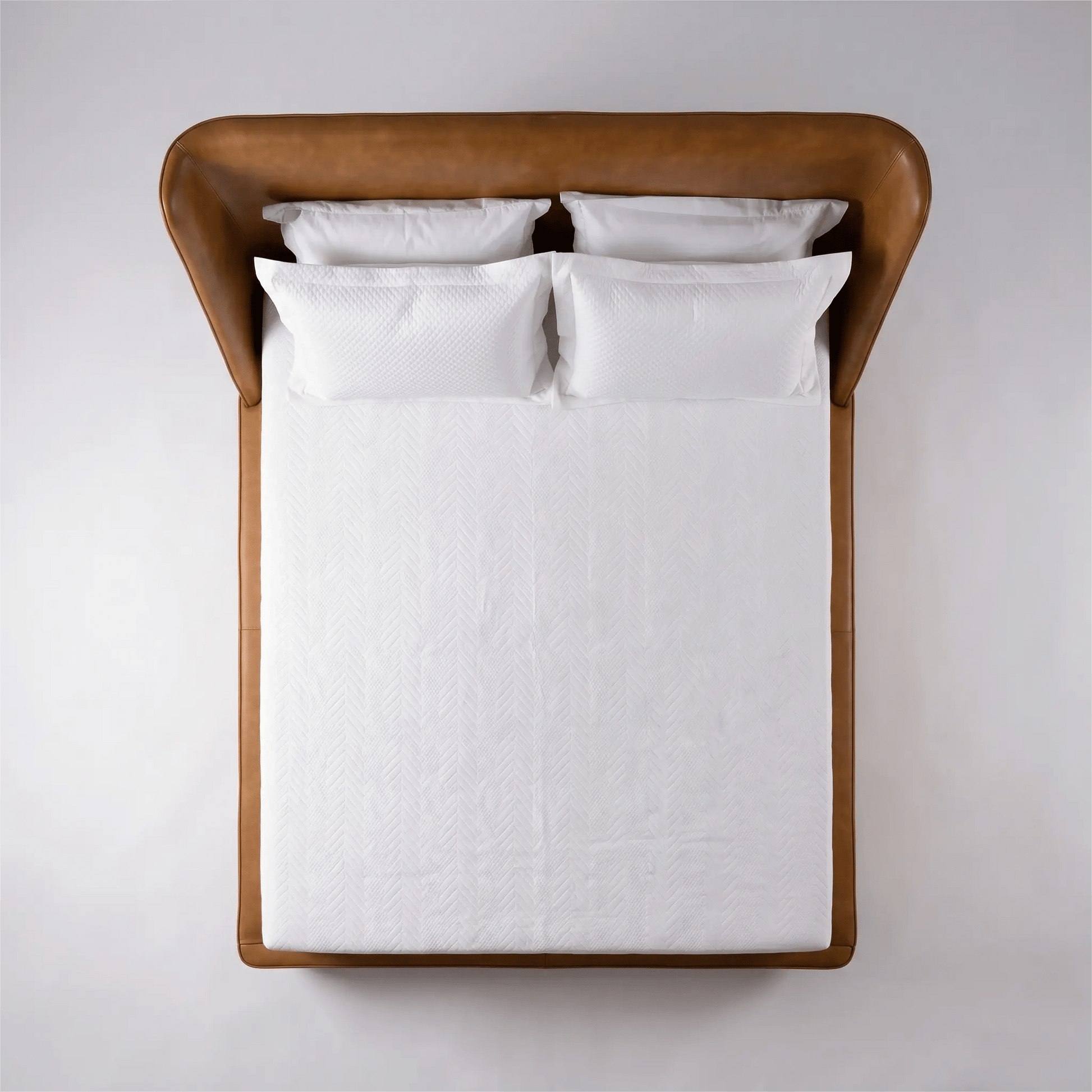 Cama estofada marrom com cabeceira alta e colcha branca, vista de cima