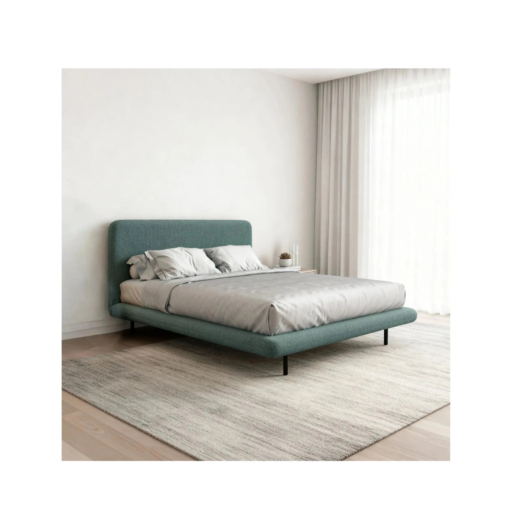 Cama estofada verde-azulada com cabeceira alta, roupa de cama branca e travesseiros.