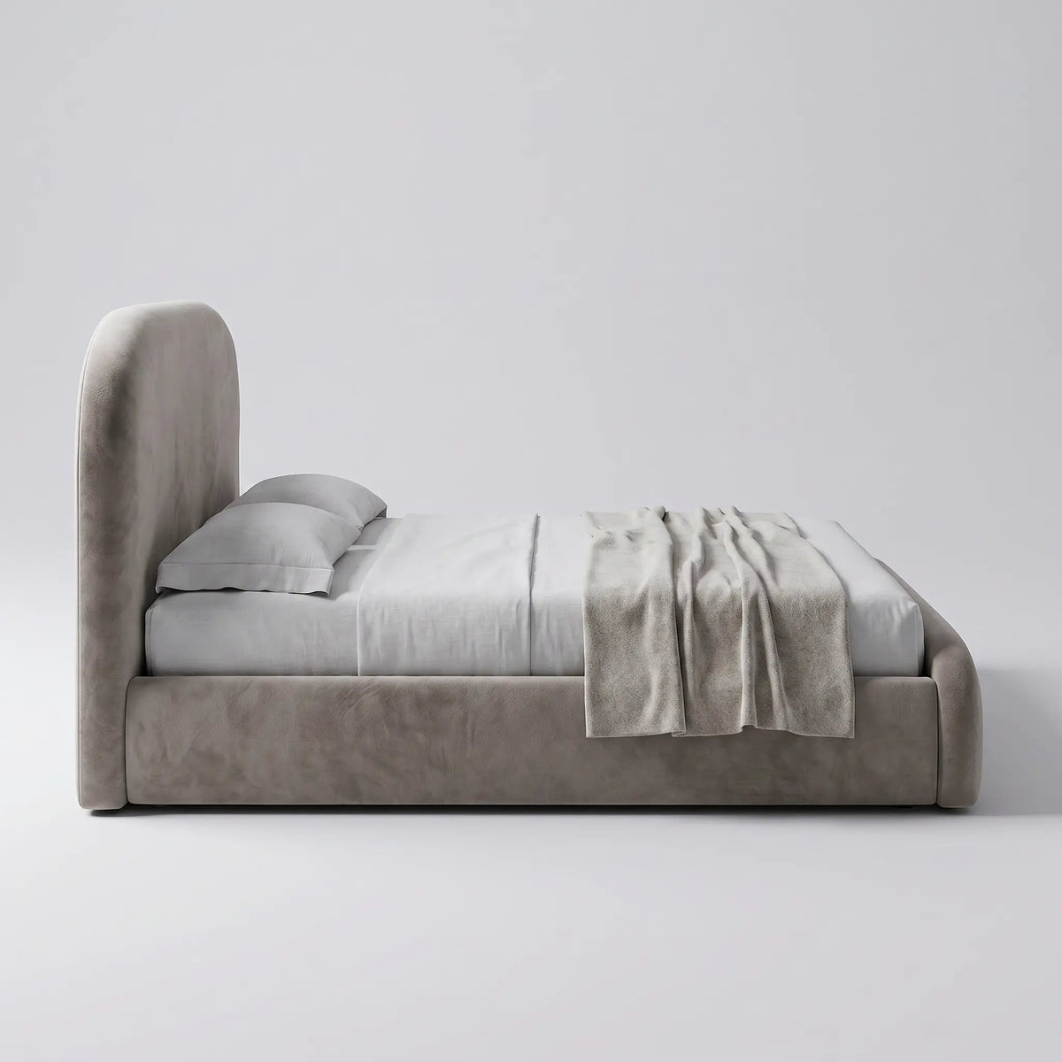 Cama estofada clara baixa com travesseiros e manta dobrada sobre a base