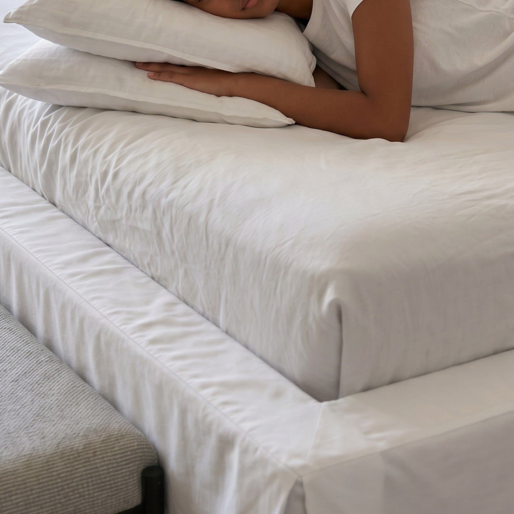 Capa branca da cama queen com dobras e tecido texturizado na lateral do colchão