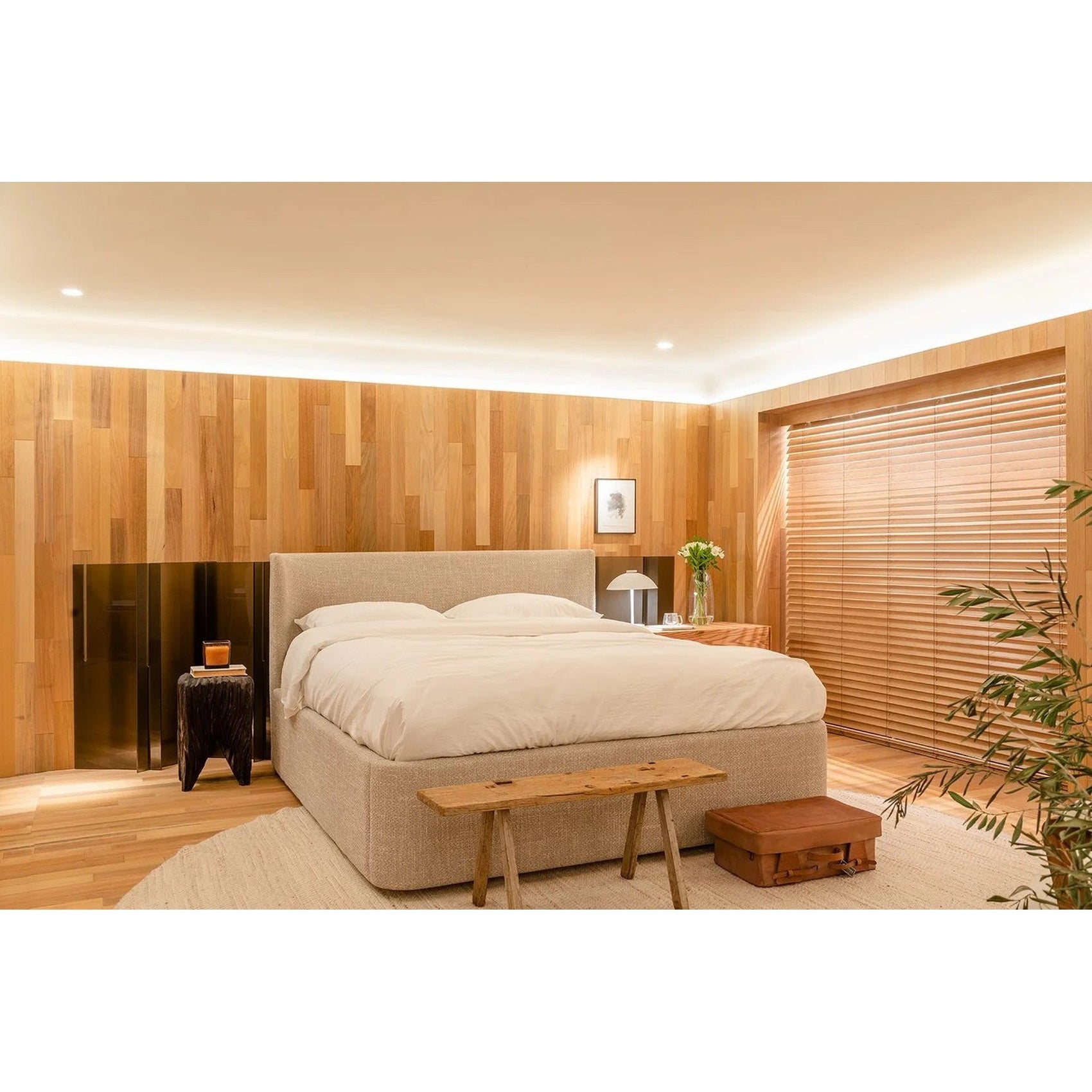 Cama estofada bege com roupa de cama branca e travesseiros, em quarto moderno