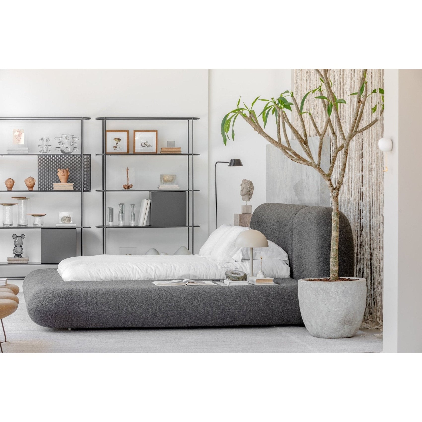 Cama orgânica estofada cinza com roupa de cama branca, almofadas e cabeceira alta
