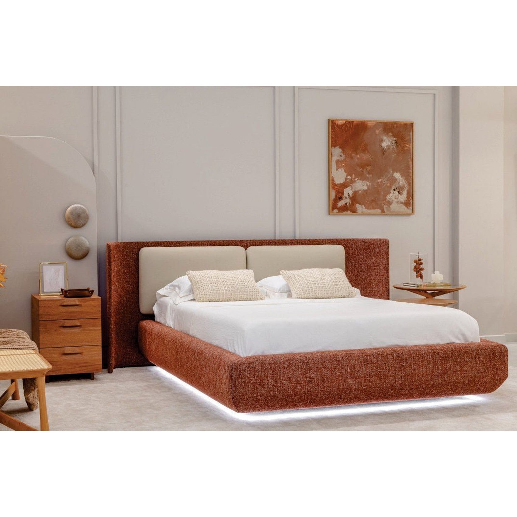 Cama estofada marrom com cabeceira alta, roupa de cama branca e almofadas em tom claro