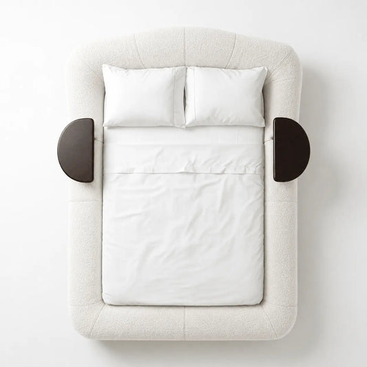 Cama queen estofada bege claro com travesseiros brancos e dois apoios laterais arredondados