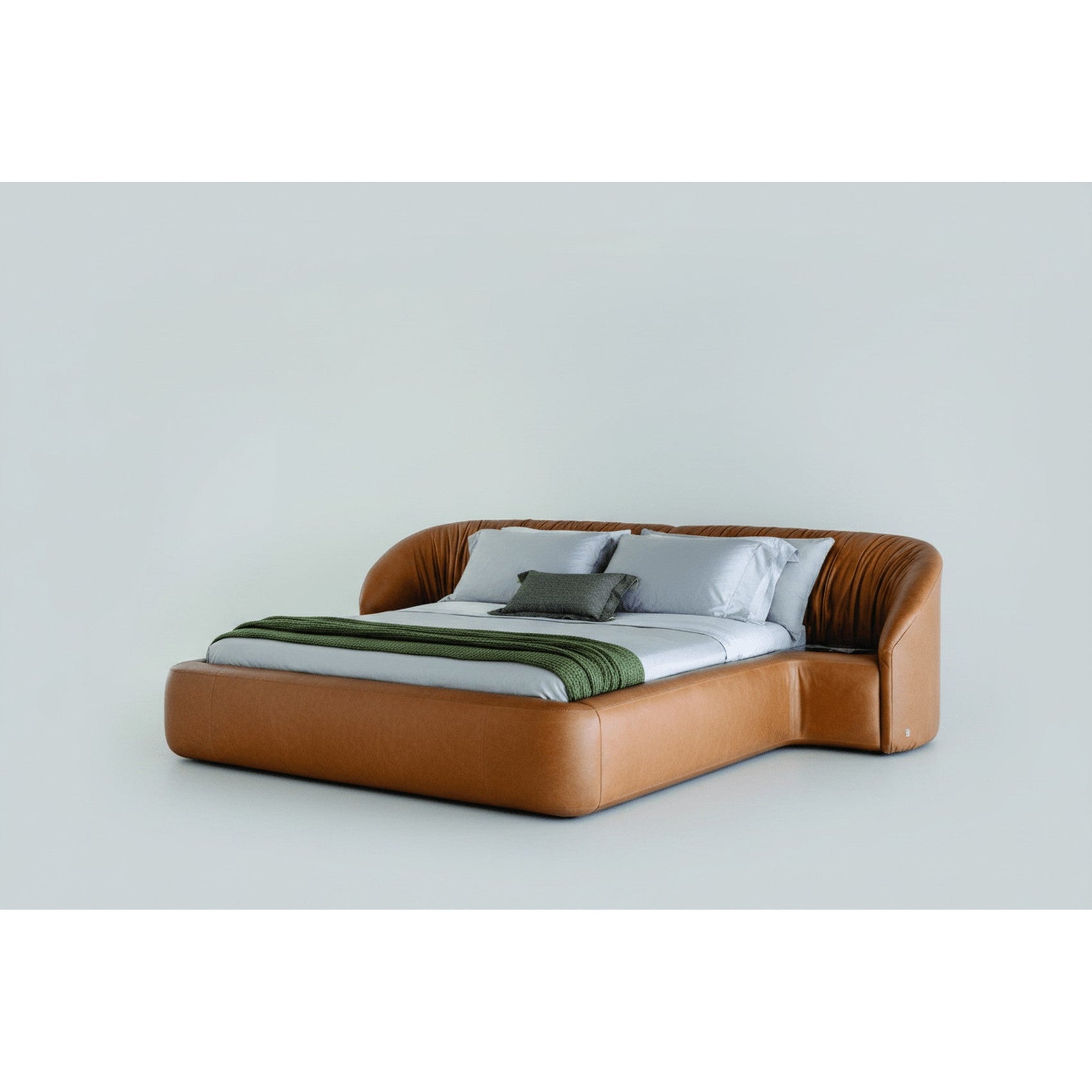 Cama baixa estofada marrom com roupa de cama clara e manta verde, vista lateral.