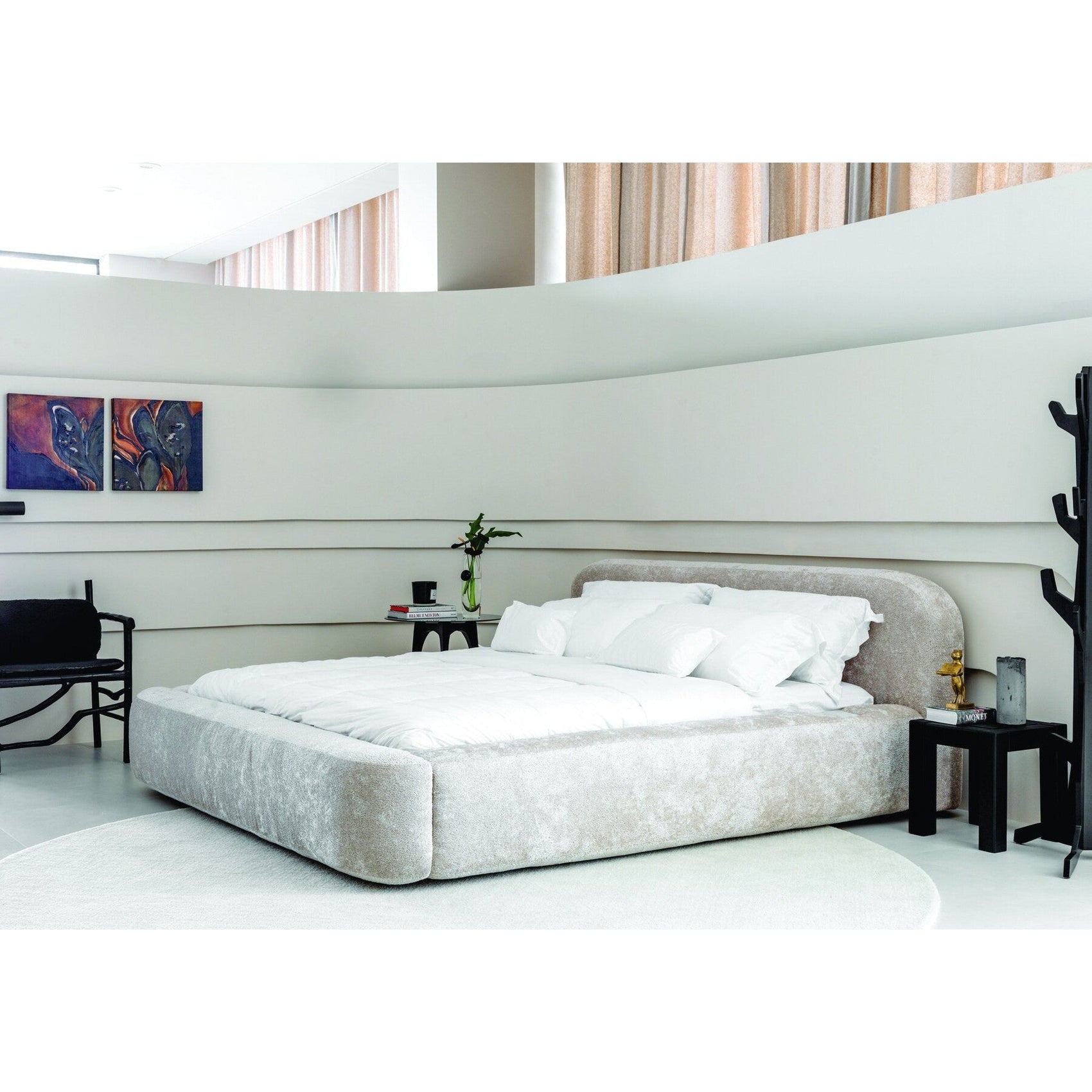 Cama estofada cinza claro com cabeceira alta curvada e travesseiros brancos