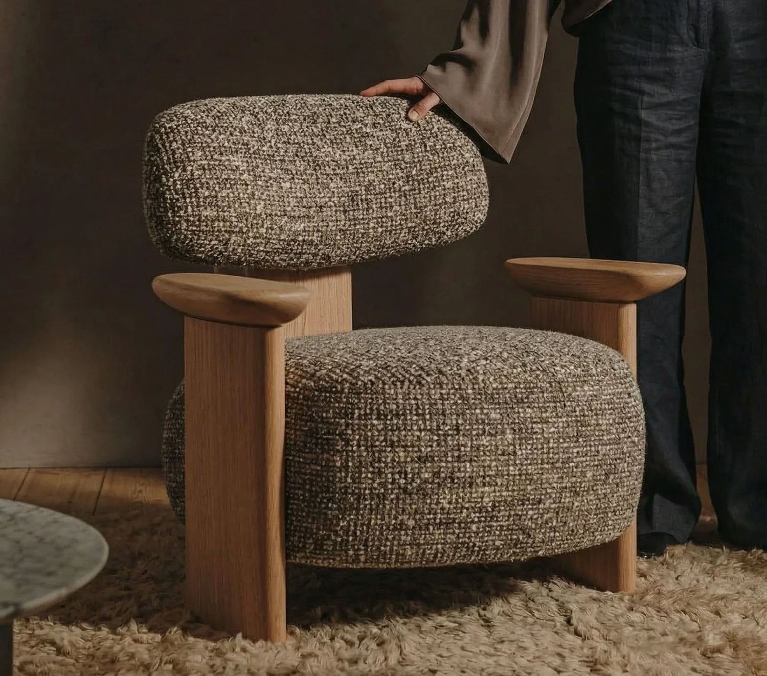 Poltrona de design contemporâneo com assento e encosto estofados, base de madeira clara