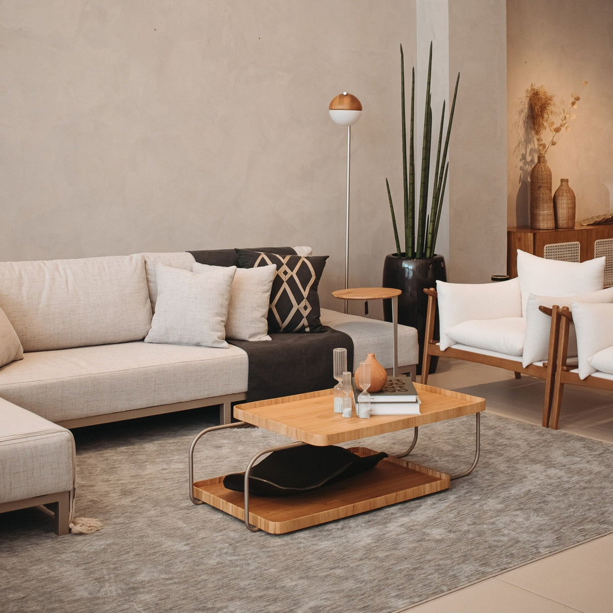 Mesa de centro de bandejas em sala de estar com sofá, poltrona e planta em vaso alto