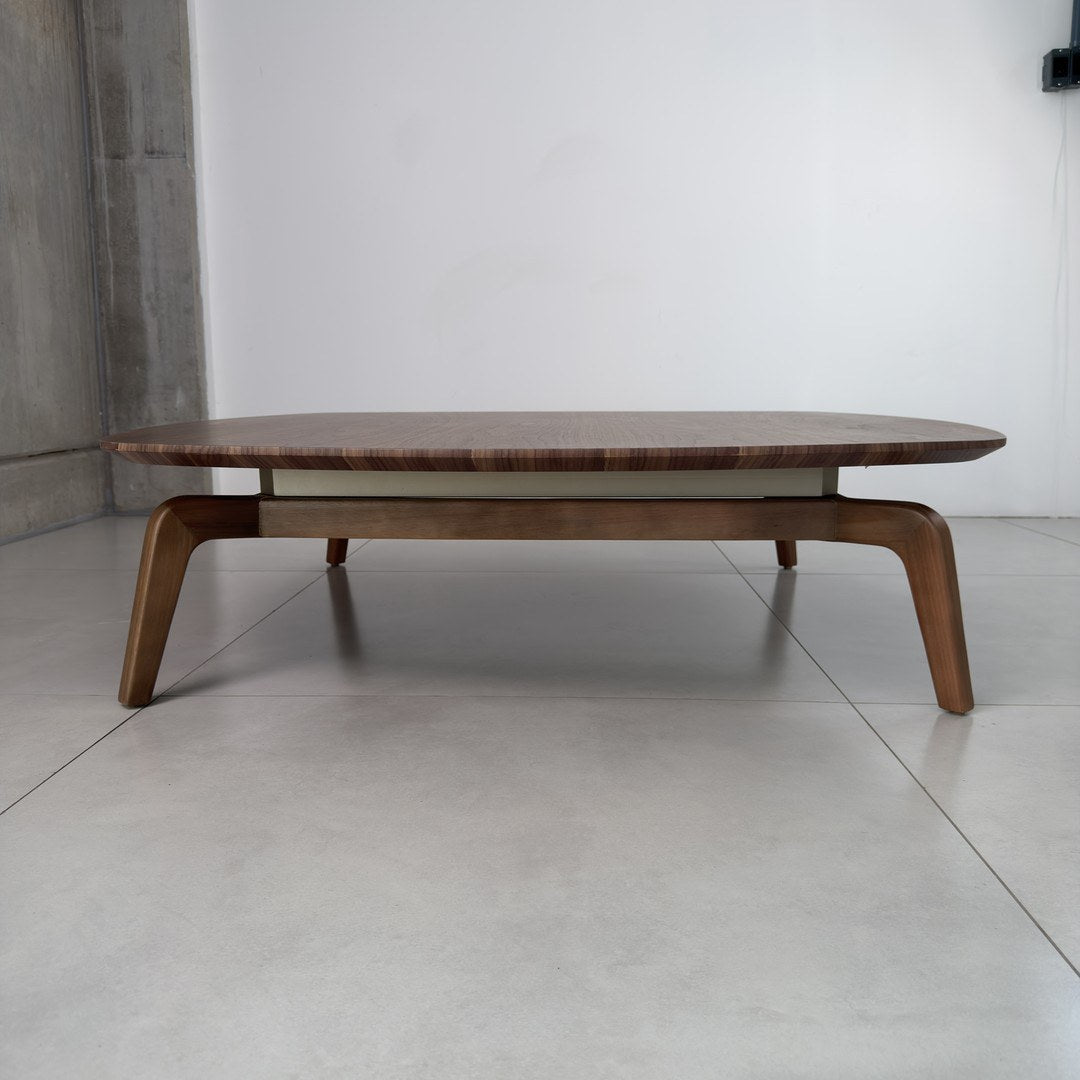 Mesa de centro de madeira em ambiente com piso de porcelanato e parede de concreto, vista frontal