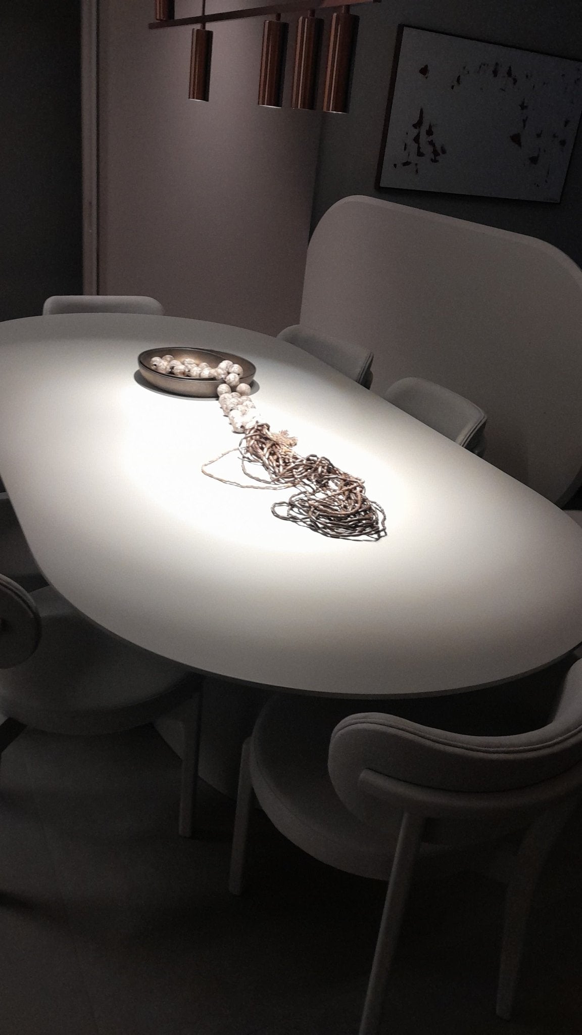Mesa de jantar oval de tampo iluminado com peça decorativa em sala de jantar com cadeiras e pendentes