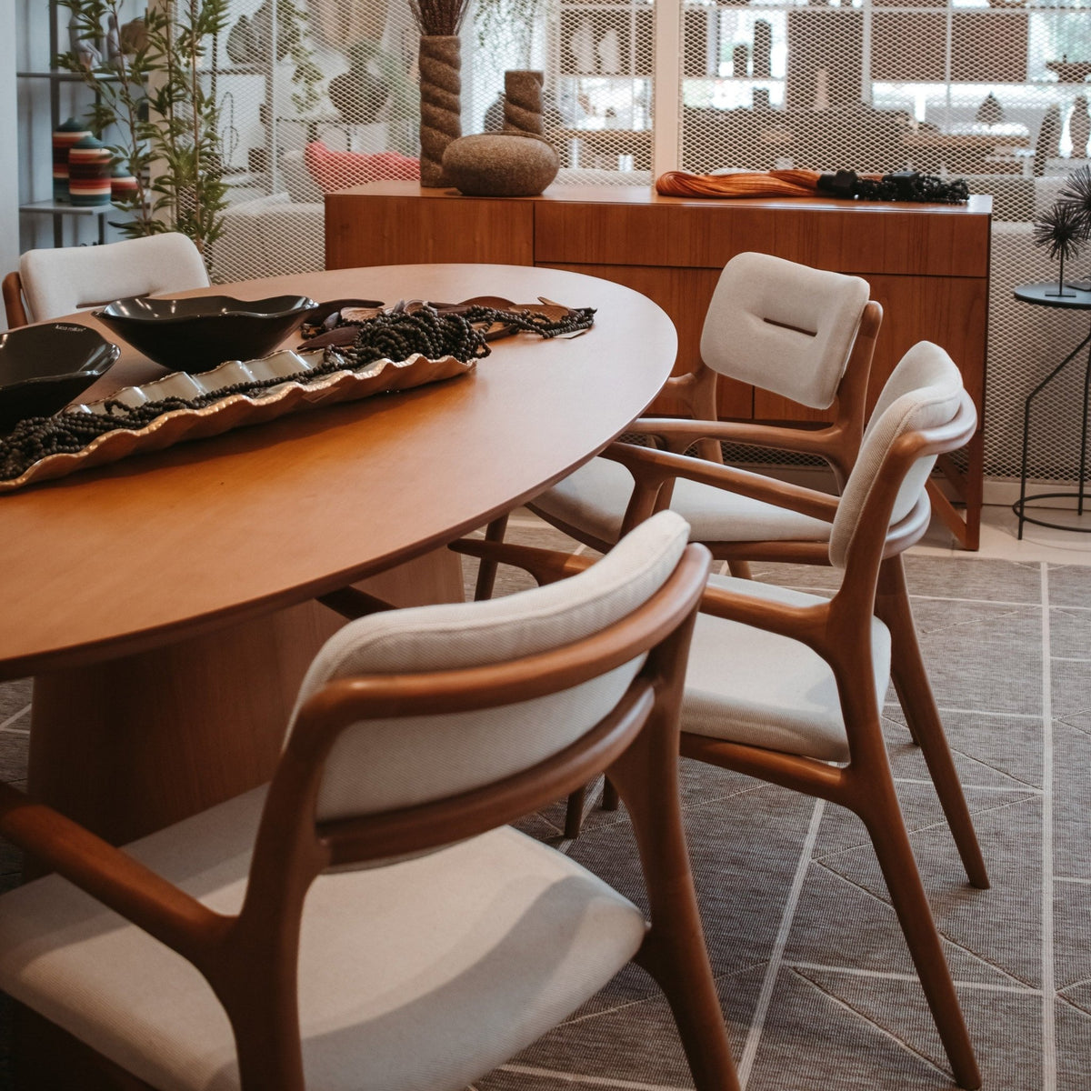 Mesa de jantar oval com centro de mesa decorativo e cadeiras de braço em sala de jantar com aparador
