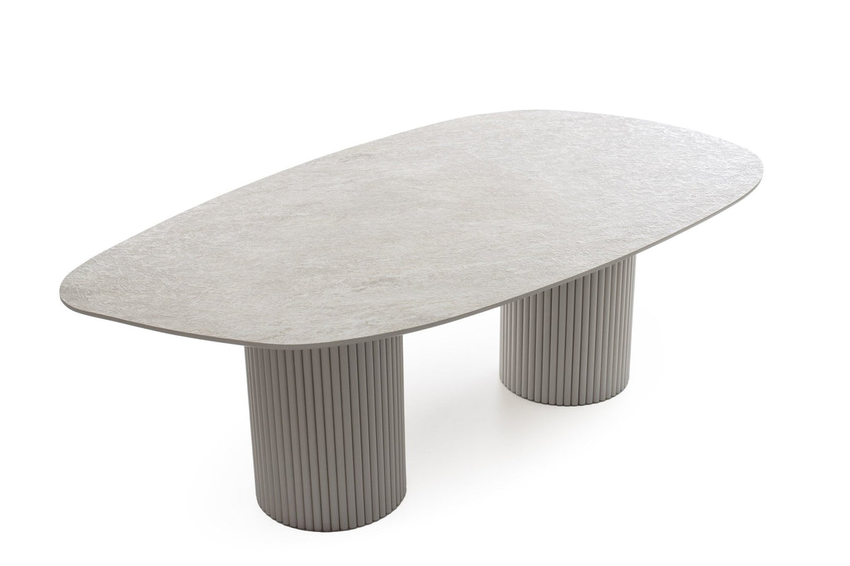 Mesa de jantar de tampo orgânico com textura de pedra sobre duas bases cilíndricas caneladas