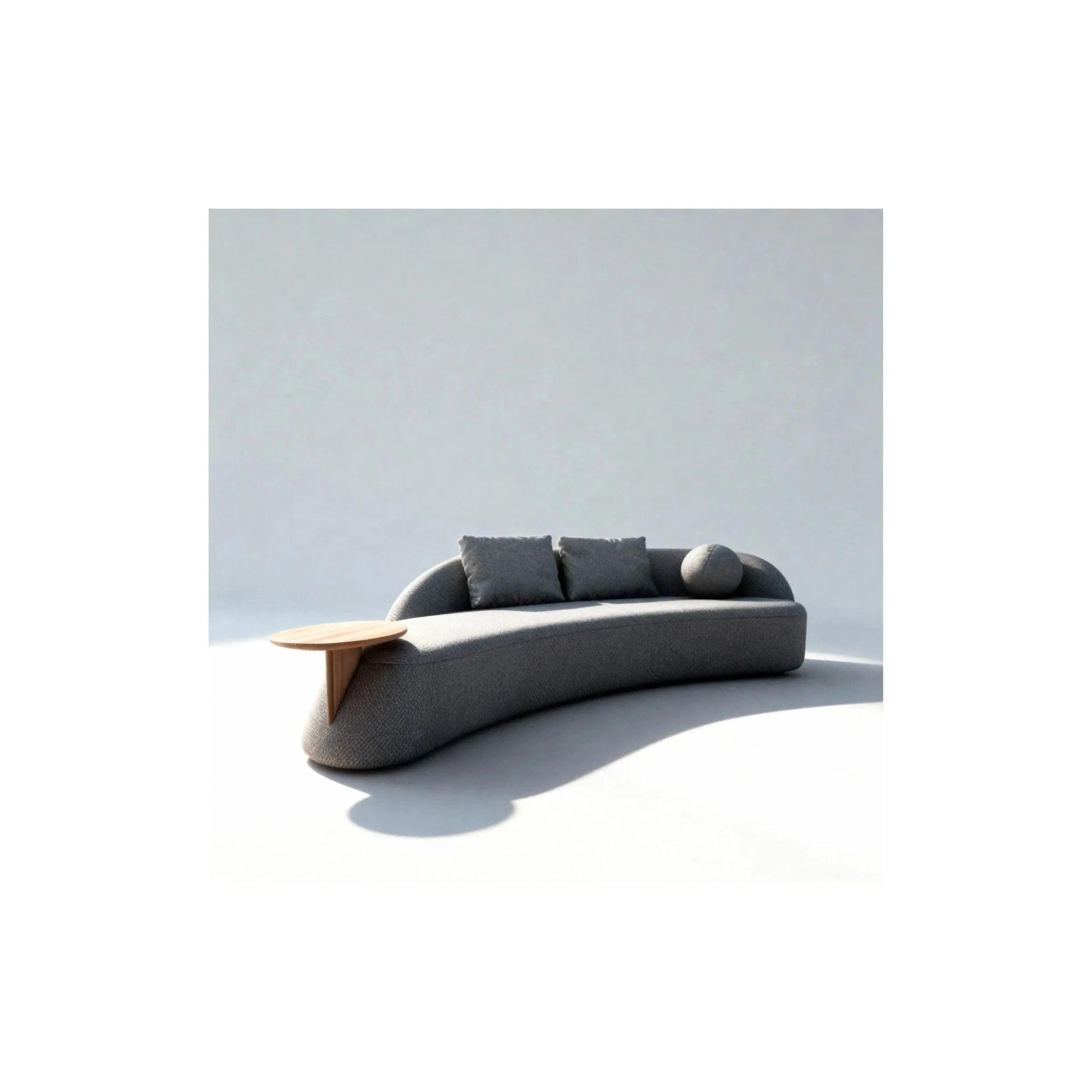 Sofá cinza escuro com chaise, almofadas claras e mesa lateral de madeira.