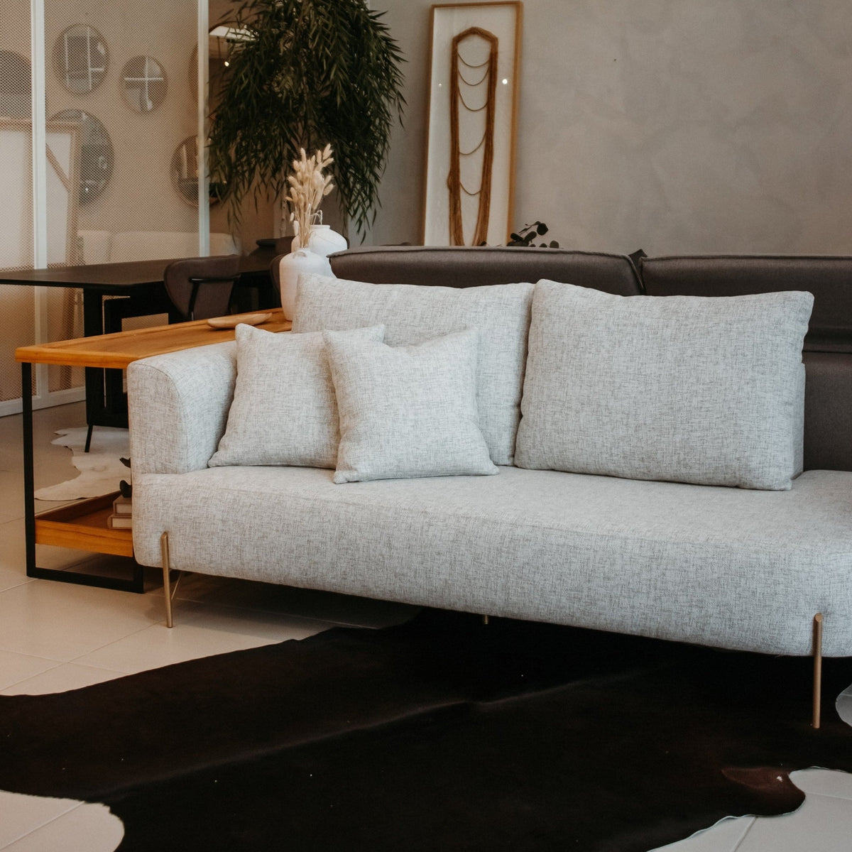 Sofá com almofadas soltas e decorativas no encosto em sala de estar com tapete de pelo e mesa de madeira